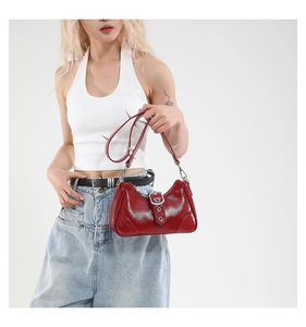 Détail du sac rouge en cuir verni avec des clous punk argentés et une boucle de ceinture