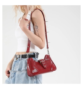Gros plan du sac hobo en cuir verni rouge avec bandoulière à rivets argentés punk