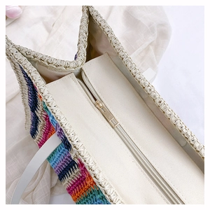 Detail of rainbow straw tote bag featuring secure zipper closure and canvas lining