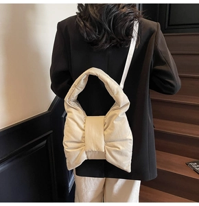 Close-up of cream white quilted nylon tote bag featuring a large decorative bow design