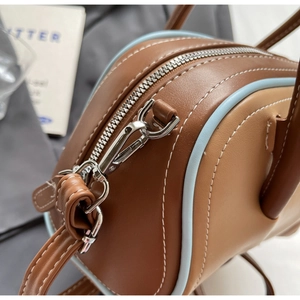 Detailed close-up of two-tone leather handbag with blue edging and silver metal zipper