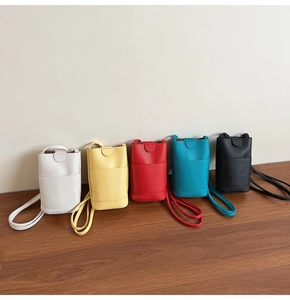 Vertical pebble grain mini crossbody phone bags shown in five vibrant colors on a table