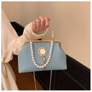 Detail of light blue textured evening bag with pearl handle and gold metal tassel accents