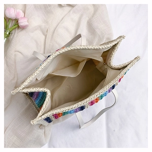 Detail view of rainbow straw tote bag interior with beige lining and zipper closure
