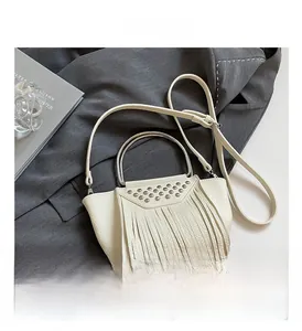 Dettaglio borsa a mano in pelle bianca con borchie argentate e decorazione a frange