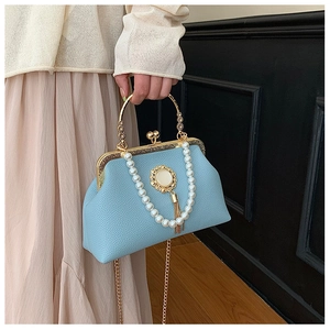 Detail of light blue leather evening bag with pearl chain and golden flower emblem