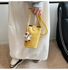 Détail d'un mini sac bandoulière en cuir jaune grainé avec un pendentif canard mignon