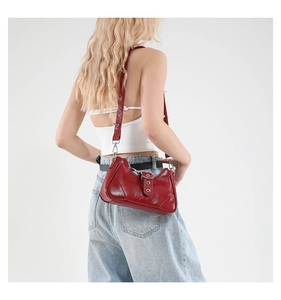 Détail d'un sac à bandoulière rouge verni avec des rivets argentés et boucle métallique