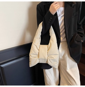 Close-up of cream quilted puffy bow-shaped tote bag shown in a minimalist fashion setting