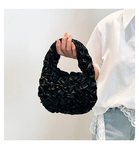 Detail of black pleated lace handbag featuring intricate ruffled texture and satin finish