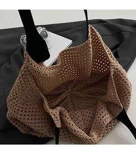 Detail of open-top brown crochet tote bag with black leather straps and spacious interior
