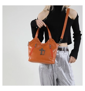 Close-up of orange vintage leather tote bag with lychee texture and cross pendant