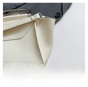 Dettaglio ravvicinato di borsa in pelle martellata bianco crema con manici ad anello argento