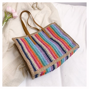 Detail of colorful rainbow woven straw tote bag with brown faux leather shoulder straps