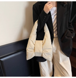 Detail of a creamy bow-shaped quilted shoulder bag featuring soft padded texture and modern design