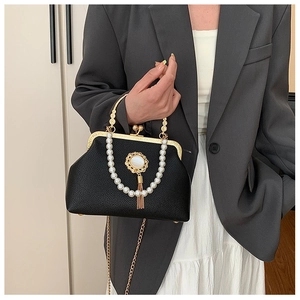 Baroque black evening bag with pearl handle and gold tassel on a gray blazer suit
