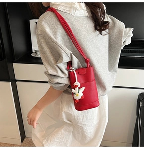 Gros plan du mini sac à bandoulière rouge en cuir grainé avec un charm de canard blanc