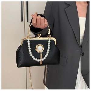 Detail of vintage black kiss-lock handbag with pearl handle and gold tassel decoration