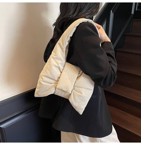 Detail of a beige bow-shaped puffer shoulder bag with quilted down-filled texture