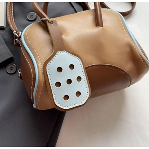 Close-up of retro color-block leather bowling bag with blue piping and round tag