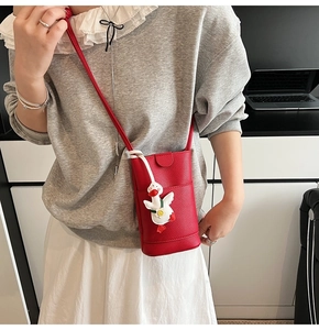 Détail du petit sac bandoulière rouge texture litchi avec breloque petit canard