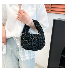 Detail of black pleated ruffle handbag with textured satin-like floral clouds and handle