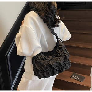 Detail of a black pleated puffy cloud bag showing sleek nylon texture and ruffles