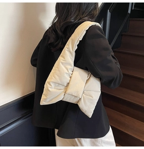 Detail of a beige bow-shaped puffer tote bag showing the soft quilted nylon texture