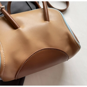 Detailed close-up of macaron bowling bag with caramel leather and blue contrast edges