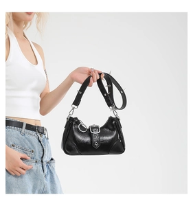 Detail der schwarzen Punk-Schultertasche mit Metallstacheln und glänzendem Lackleder
