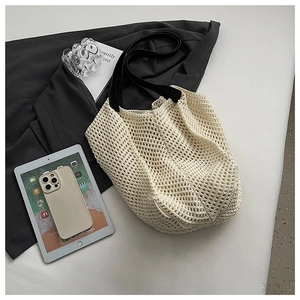 Close-up of knit tote bag showing off-white crochet mesh and black leather handles