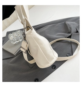 Detail of white lychee leather tote bag with side triangular structure and silver hardware
