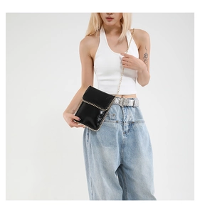 Detail of black glossy leather crossbody bag with punk style metal chain edge stitching
