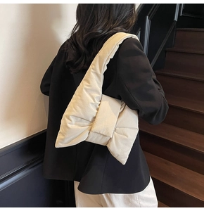 Detailed back view of a beige puffy bow-shaped tote bag worn over a black blazer