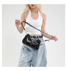 Detail der schwarzen Lackledertasche mit silbernen Schnallen und Punk-Nieten-Schultergurt