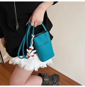 Mini sac à bandoulière en cuir turquoise avec une breloque en peluche de canard blanc