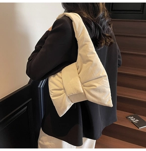 Close-up of cream quilted nylon tote bag featuring a large decorative bow and soft texture