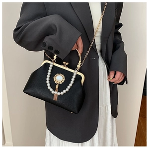 Close-up of vintage black leather clutch bag with pearl handle and golden tassel detail