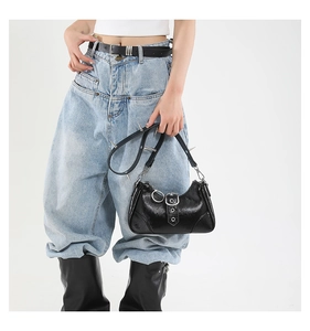 Détail du sac punk noir brillant avec des clous métalliques argentés et des boucles