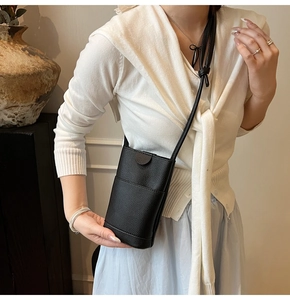 Détail d'un sac à bandoulière noir pour téléphone avec texture grainée et rabat épuré