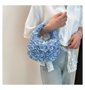 Detail of light blue pleated satin handbag showing elegant wavy texture and cloud shape