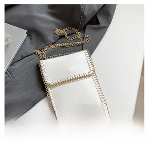 Detail of white mini crossbody bag with woven edges and a golden chain strap