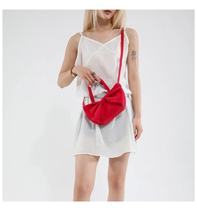 Détail du sac cabas rouge avec nœud en toile et fine bandoulière sur un mannequin