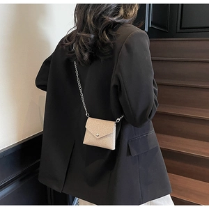 Close-up of champagne gold mini crossbody bag with silver chain strap on fashion model