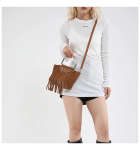 Close-up of brown leather fringe bag with metallic studs and solid metal handle