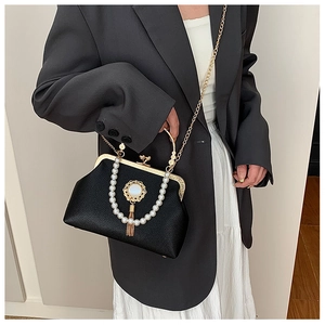 Close-up of baroque style black leather bag with pearl handle and tassel detail