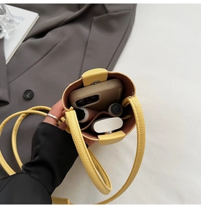 Détail d'un mini sac bandoulière jaune en cuir grainé montrant l'espace de rangement