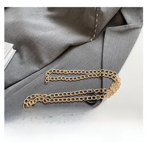 Detailed shot of golden chain strap and black button on grey twill crossbody phone bag