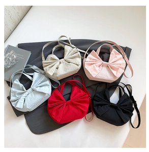Vue de dessus de cinq sacs cabas en forme de nœud de couleurs variées avec bandoulière