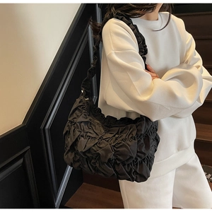 Detail view of the pleated black puff shoulder bag showing the unique ruched fabric texture